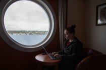 Visão de perfil de uma jovem mulher trabalhando em seu laptop em um barco — Fotografia de Stock
