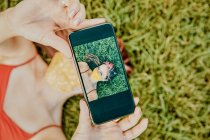 Junge Frau im Gras macht Selfie mit Gesichtsmaske — Stockfoto