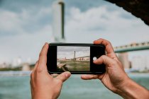 Рука тримає мобільний телефон з видом на місто — стокове фото