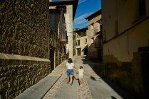 Mère et fille marchant dans une ruelle avec de vieilles maisons à Mora — Photo de stock