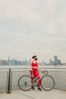 Jovem ciclista feminina usando máscara facial com bicicleta à beira-mar — Fotografia de Stock