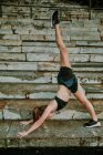Atleta femminile che si estende su gradini durante il tramonto — Foto stock