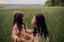 Smiling mother and daughter and talking in field — Stock Photo