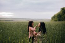 Улыбаясь матери и дочери и разговаривая в поле — стоковое фото