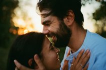 Hombre riendo mientras besar esposa al aire libre al atardecer - foto de stock