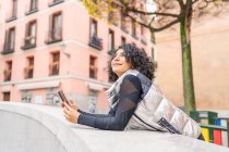 Жінка насолоджується містом і використовує свій смартфон — стокове фото
