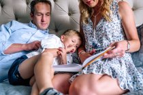 Young Boy picking nose while mom reads him a story — Stock Photo