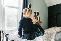 Dos niños juntos en una habitación hablando de renos y Santa Claus - foto de stock
