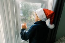 Kleiner Junge schaut ins Fenster, glückliches Kind im Winter — Stockfoto