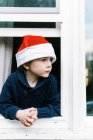 Маленький хлопчик дивиться з вікна, щаслива дитина взимку — стокове фото