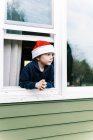Kleiner Junge schaut aus dem Fenster, glückliches Kind im Winter — Stockfoto