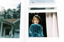 Bambino che guarda dalla finestra, bambino felice in inverno — Foto stock