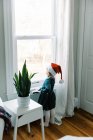 Petite fille regardant par la fenêtre attendant le Père Noël à Noël — Photo de stock