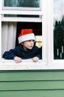 Niño mirando por la ventana, niño feliz en invierno - foto de stock