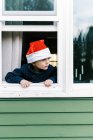 Menino olhando pela janela, criança feliz no inverno — Fotografia de Stock