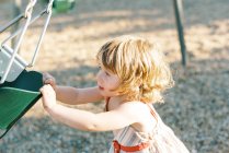 Маленькая девочка хочет качаться в качелях на детской площадке — стоковое фото