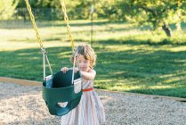 Bambina che vuole oscillare nell'altalena del bambino in un parco giochi — Foto stock