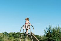 Kleines Mädchen, das auf einer Rutsche steht und sich groß und tapfer fühlt — Stockfoto