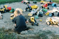 Маленький мальчик играет с множеством игрушечных грузовиков — стоковое фото