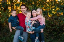 Mère, père, fils et fille famille à l'extérieur avec des arbres — Photo de stock