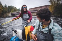 Man and woman anglers with dog in a boat during foliage season — Stock Photo