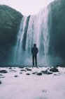 Personne debout à la cascade de Skogafoss en hiver avec de la neige au premier plan — Photo de stock