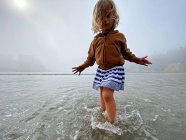 Ein junges Mädchen spielt im Ozean an einem nebligen Tag an der OR-Küste. — Stockfoto