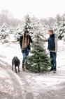 Young woman, young man and their dog at Christmas tree farm — Stock Photo