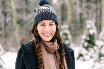 Портрет молодой улыбающейся женщины в вульгарной шляпе в снегу — стоковое фото