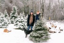 Young woman, young man and their dog at Christmas tree  farm — Stock Photo