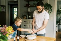 A father and son putting streusel on a peach cobbler — Stock Photo