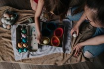 Overhead shot of sisters dying chicken eggs — Stock Photo