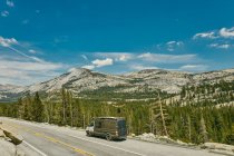 Young man standing on camper van watching views of Yosemite Park. — Stock Photo