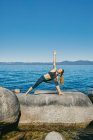 Молодая женщина практикует йогу у моря — стоковое фото