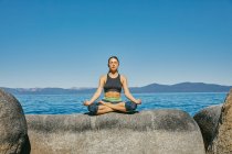 Giovane donna che pratica yoga sul mare — Foto stock