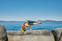 Молодая женщина практикует йогу у моря — стоковое фото