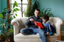 Un padre y un hijo leyendo en casa - foto de stock