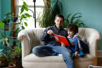 Un père et son fils lisant à la maison — Photo de stock