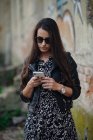 Приваблива молода жінка дивиться на свій телефон зовні і йде — стокове фото
