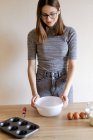 Женщина в футболке и джинсах готовит домашние кексы на кухне — стоковое фото