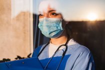 Joven mujer triste caucásico Reino Unido EE.UU. NHS EMS médico cuidador mirando a través de - foto de stock