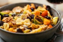 Brussels sprouts and winter squash on pasta with cranberries and walnuts. — Stock Photo