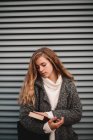 Retrato de adolescente estudante menina segurando livro de pé contra a parede cinza — Fotografia de Stock