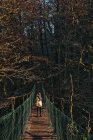 Jeune femme traversant pont suspendu — Photo de stock