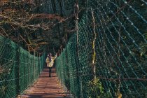 Junge Frau überquert Hängebrücke mit Kamera — Stockfoto