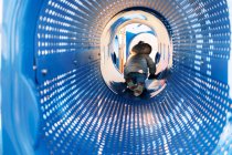 Menina pequena rastejando através do túnel no parque infantil — Fotografia de Stock