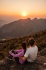Belle vue au couple de randonnée profitant du coucher de soleil du sommet de la montagne — Photo de stock