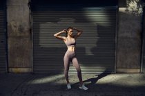 Ritratto di bella giovane donna in elegante abbigliamento sportivo moderno in posa sulla strada della città — Foto stock