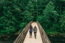 Um jovem casal desfruta de uma caminhada em uma ponte no noroeste do Pacífico. — Fotografia de Stock