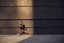 Retrato de bela jovem mulher no elegante sportswear moderno correndo na rua da cidade — Fotografia de Stock